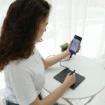 Девушка со смартфоном в руках, смартфон подключен к графическому планшету Huion HS64